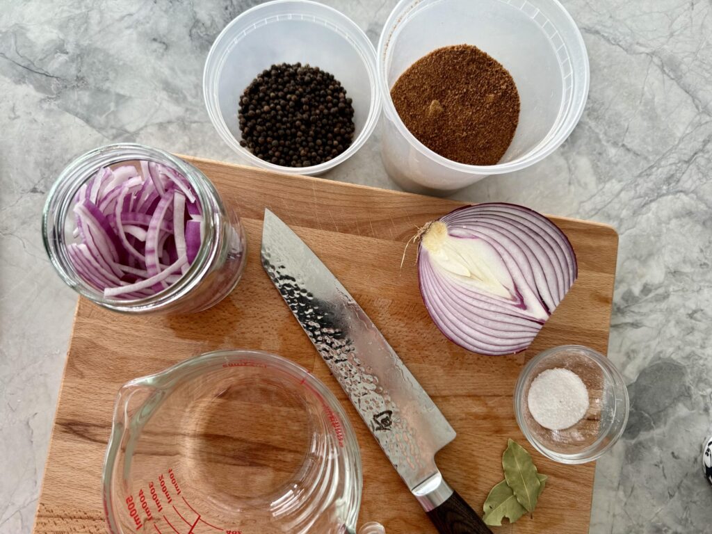 how to add flavor to pickled red onions - sliced onions with peppercorns and bay leaves